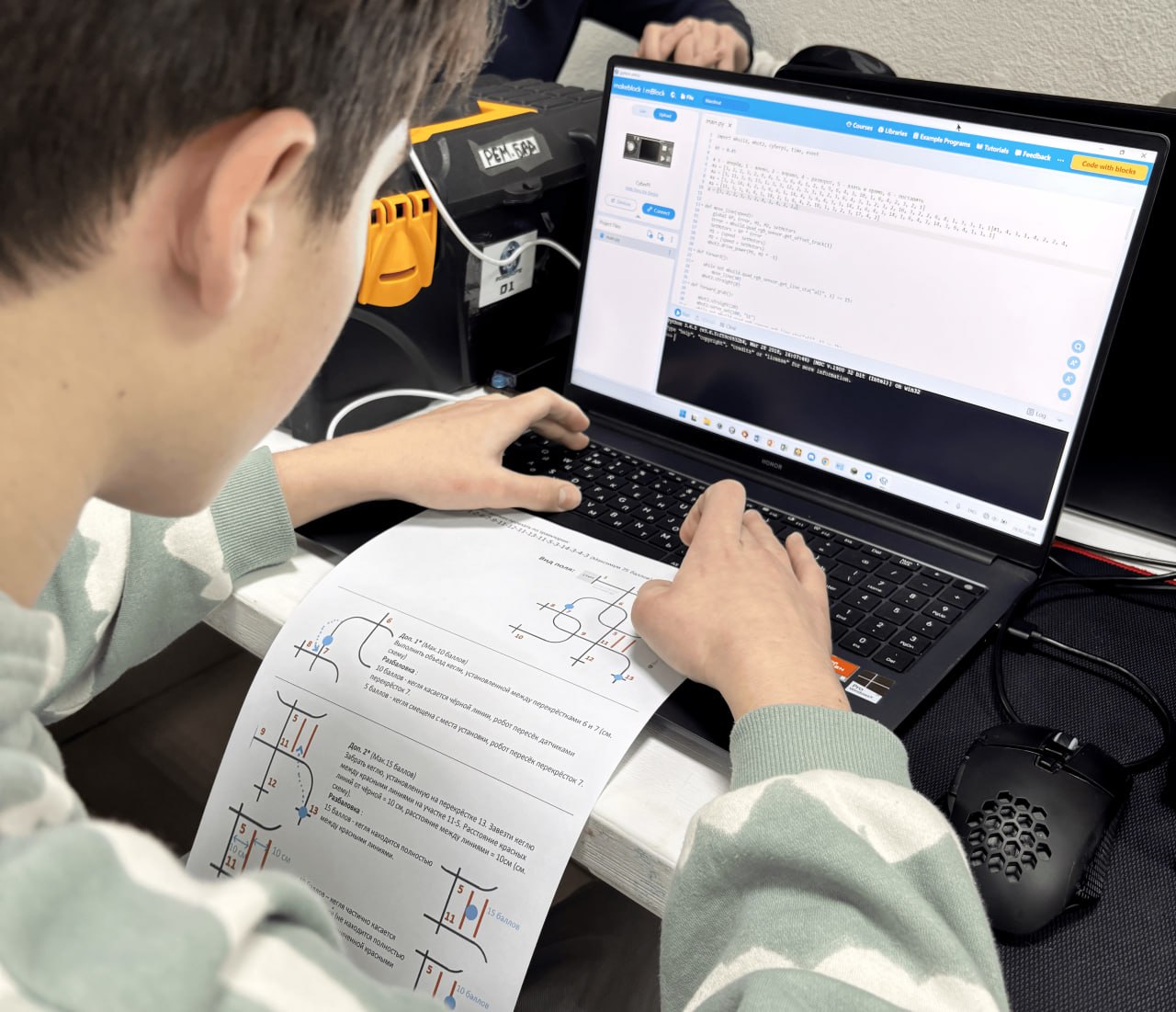 Ученик программирует робота на ноутбуке